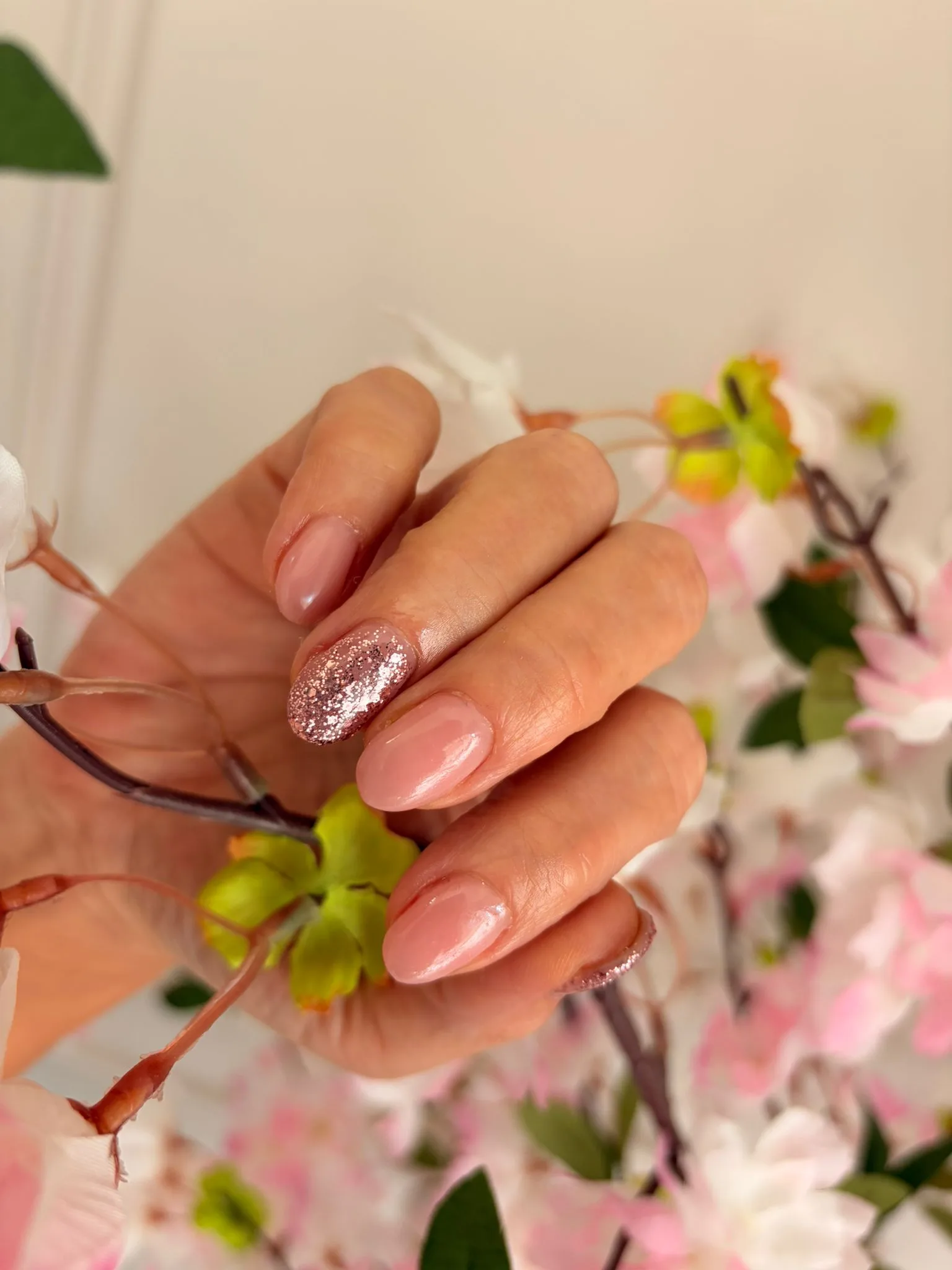 Hand met gouden ringen en een nude manicure op marmer