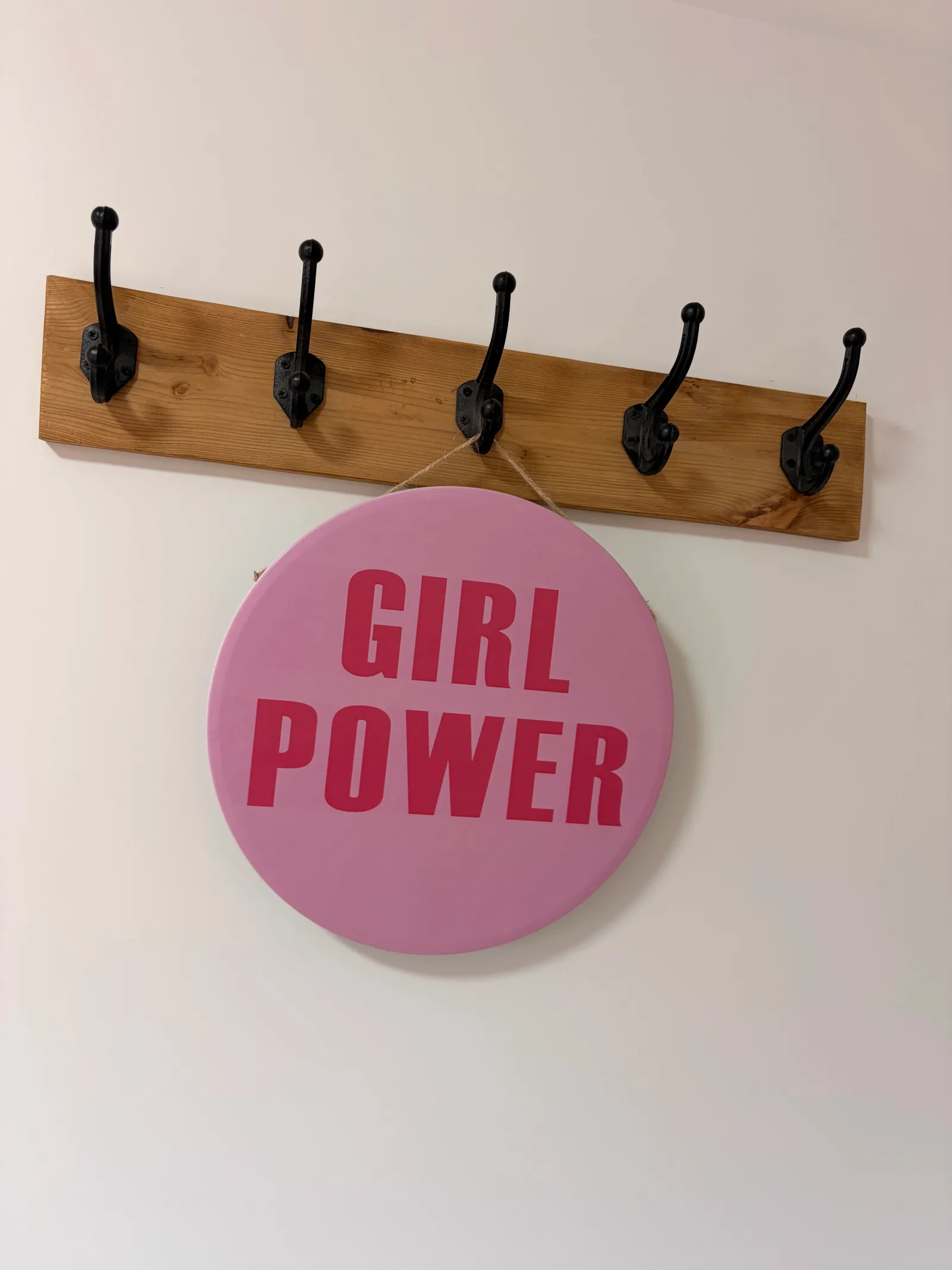 Rond Girl Power-bord aan de houten kapstok in de studio